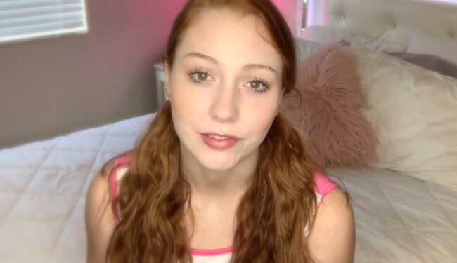 Woman with long red hair looking toward the camera indoors