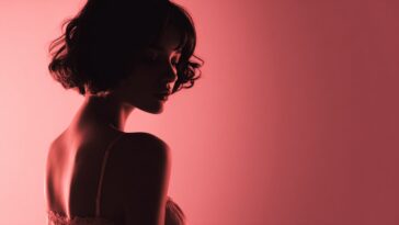 Woman in profile with short hair against a red background