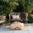 Cozy patio with wicker furniture, cushions, and a patterned pouf