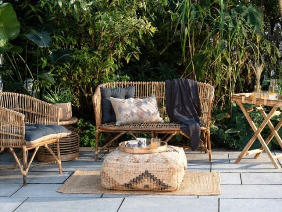 Cozy patio with wicker furniture, cushions, and a patterned pouf