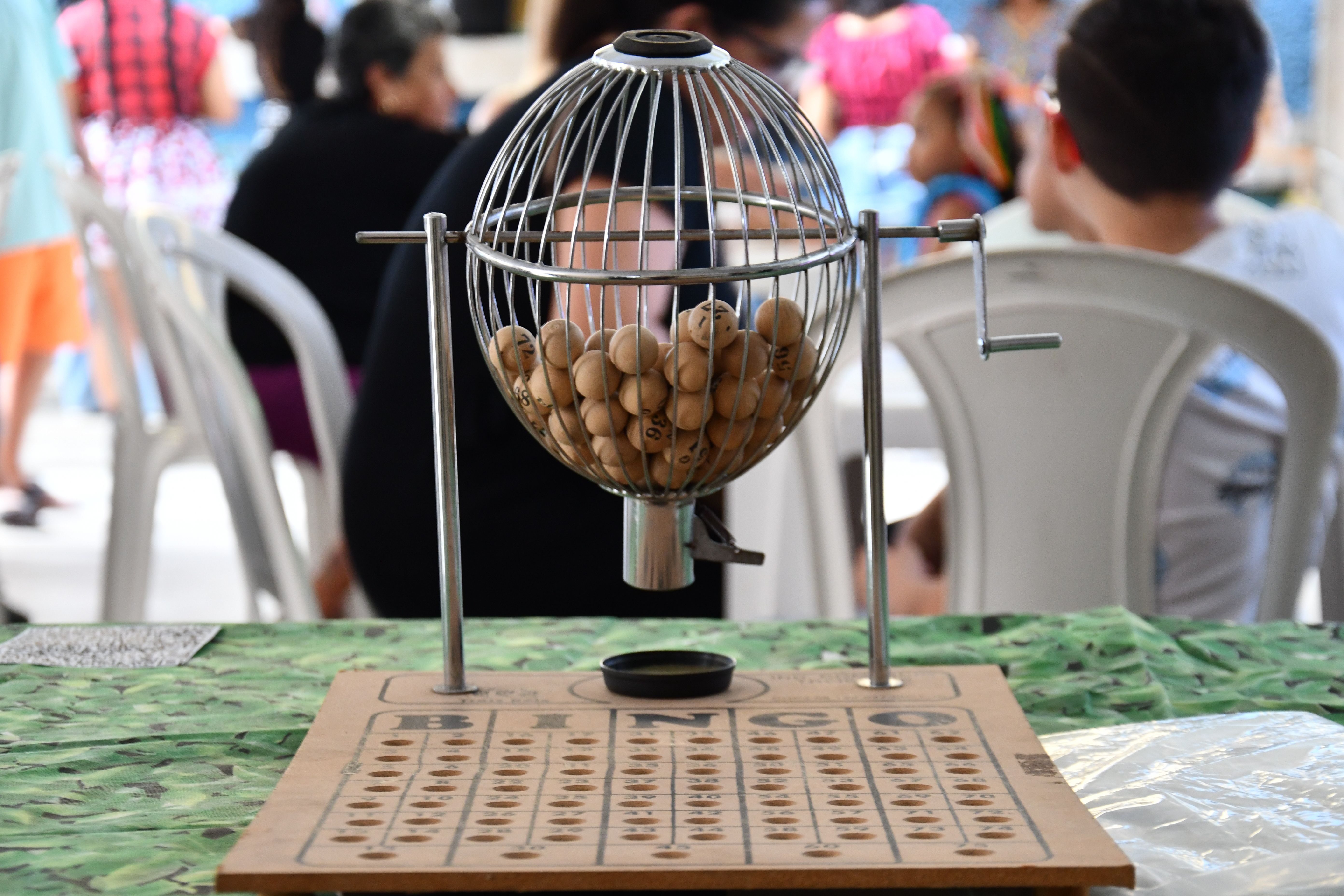 Close-up of a bingo cage with numbered balls and a board ready for play