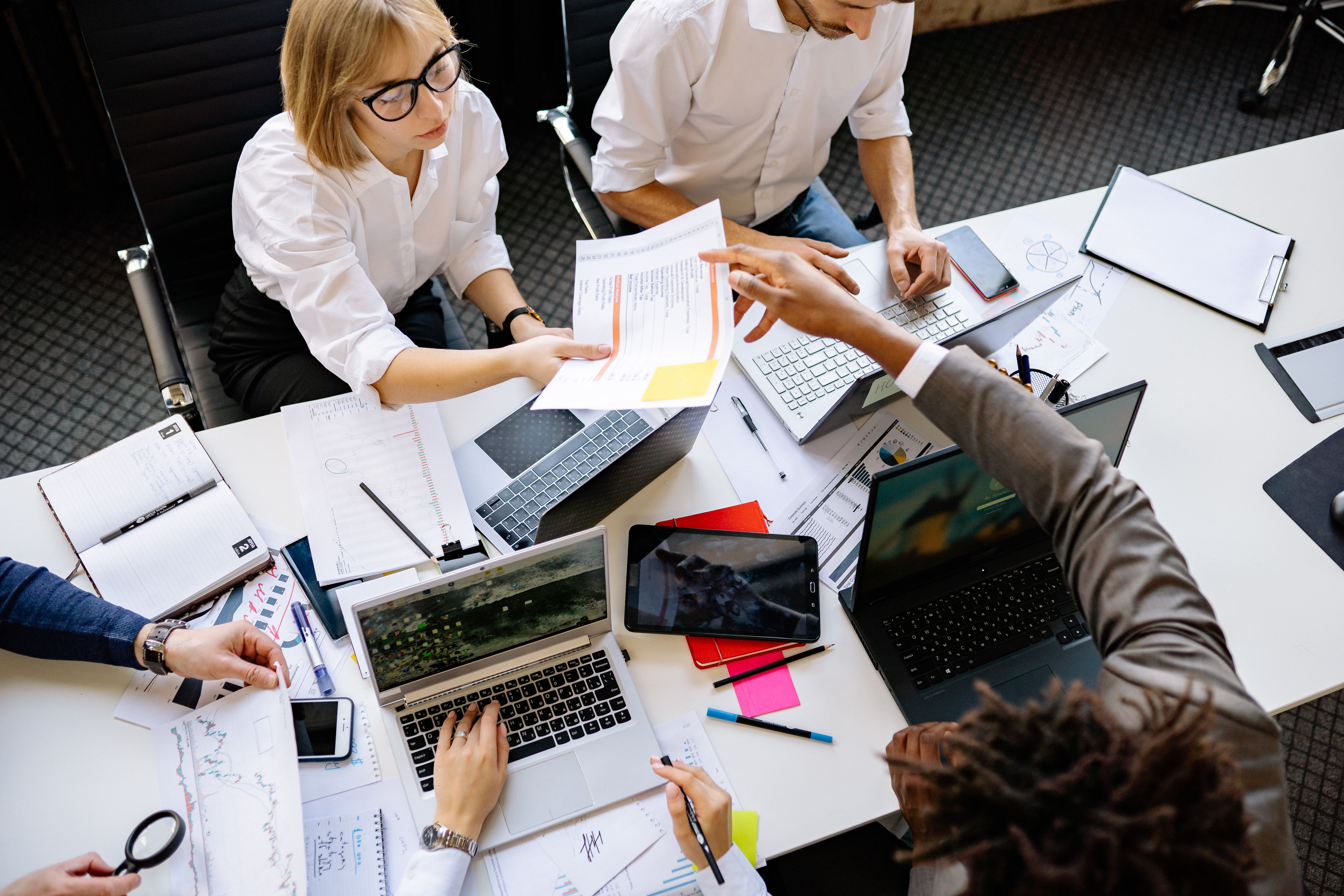 Diverse business team collaborating with laptops in a modern office, evaluating privacy-focused VPS hosting