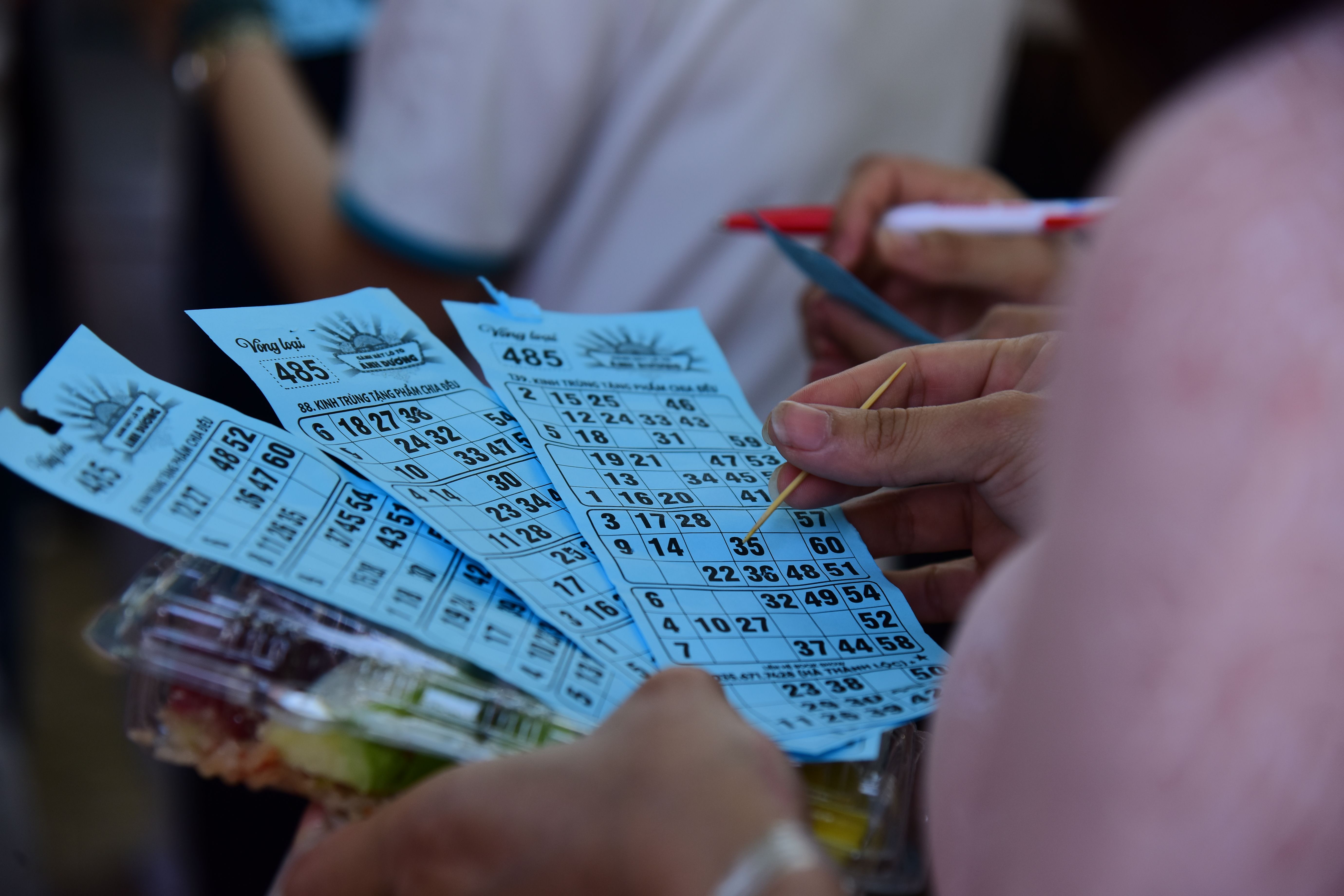 People playing bingo indoors holding blue cards with pens and markers
