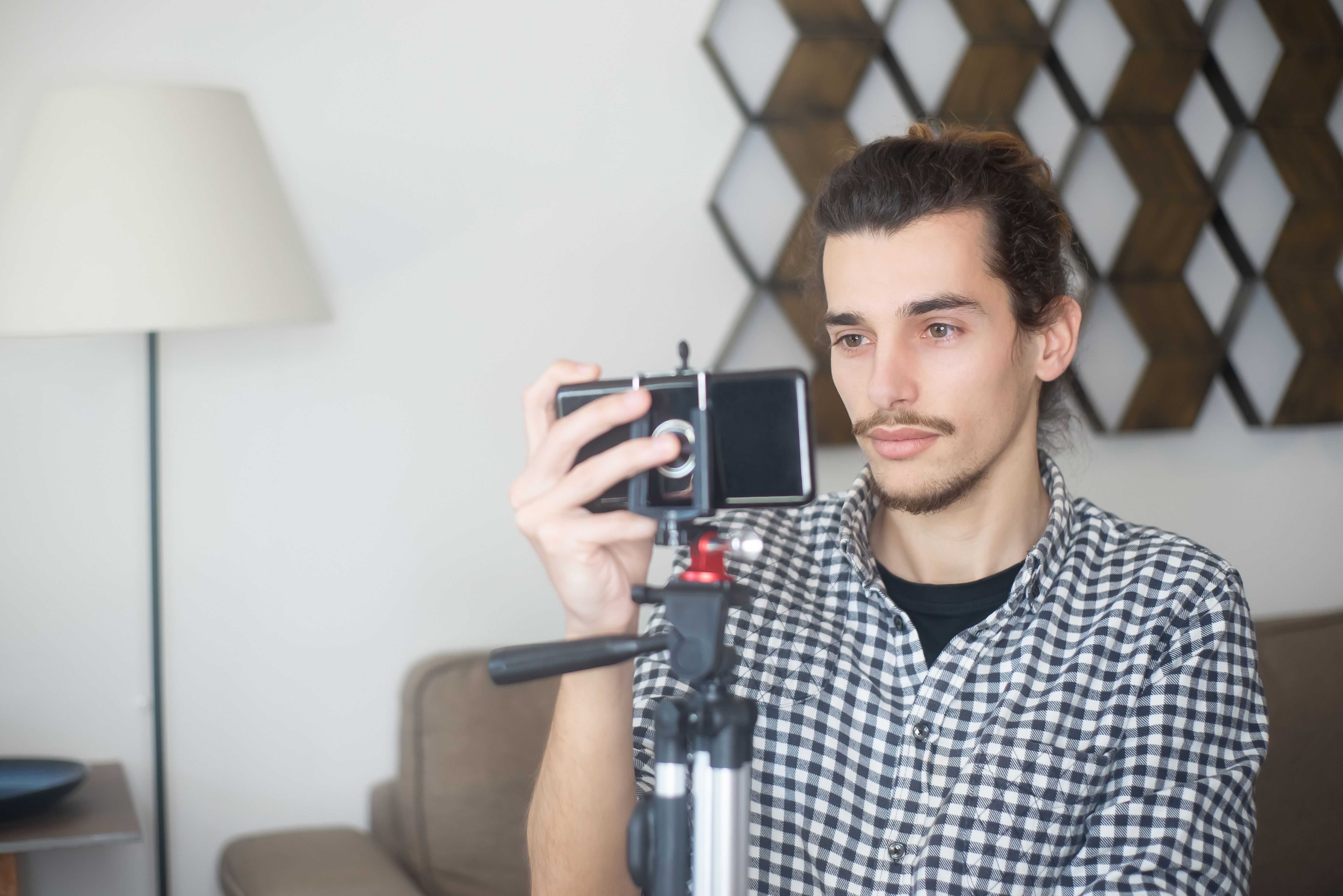 Creator using a smartphone and tripod to record an authentic video at home.