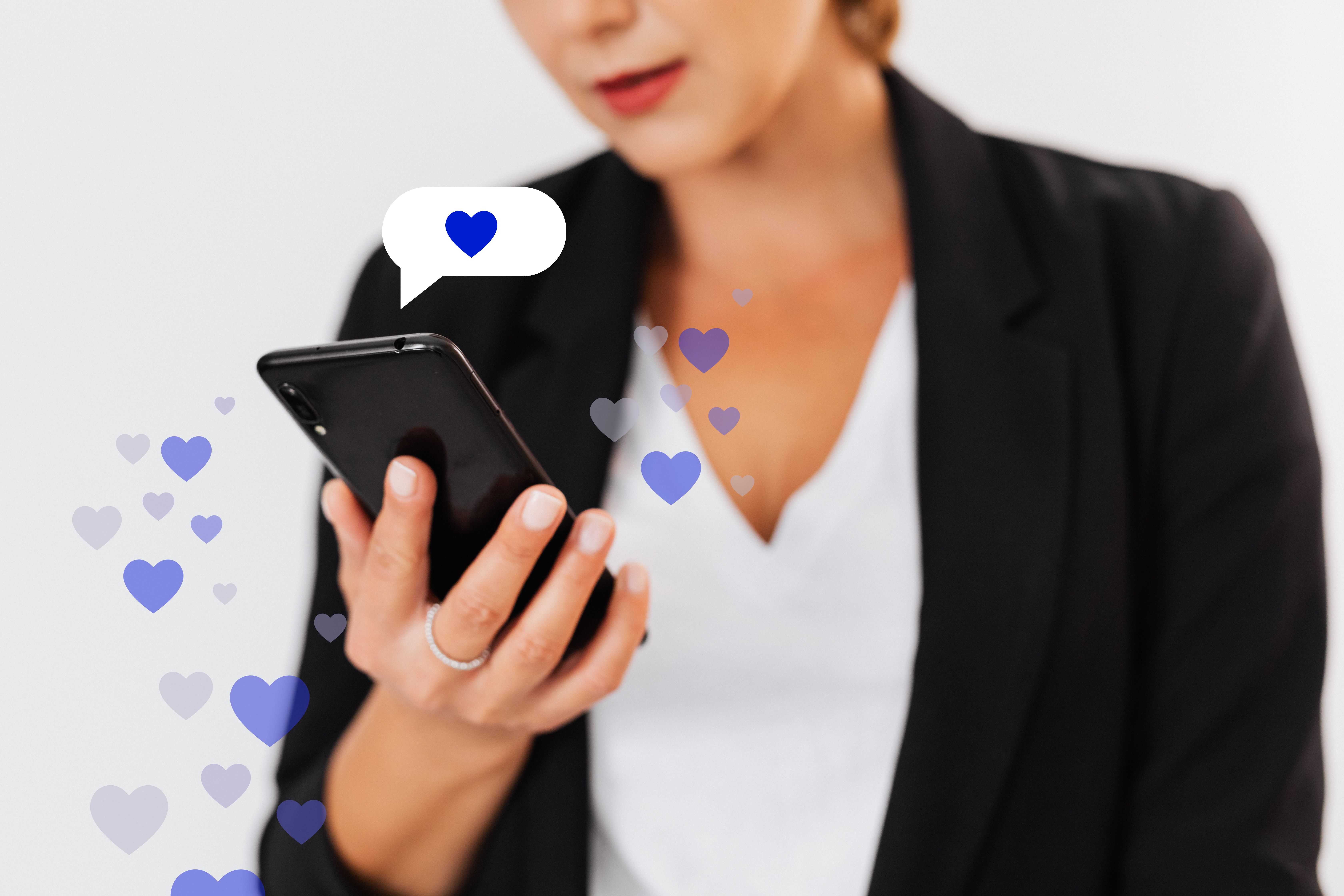 Person using a smartphone with floating heart icons, symbolizing Instagram likes and audience engagement.