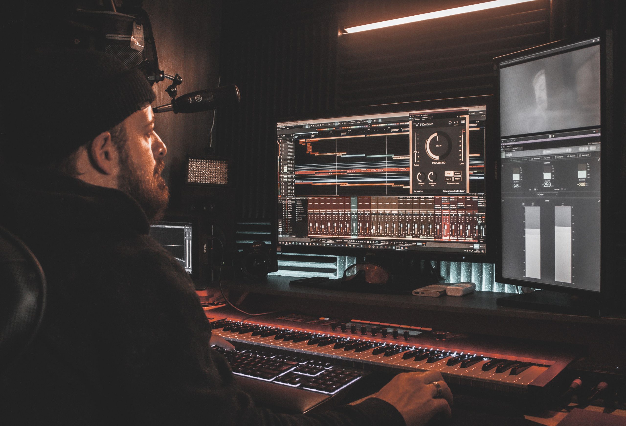 Music producer focused at a home studio workstation, shaping a track on a digital audio setup.